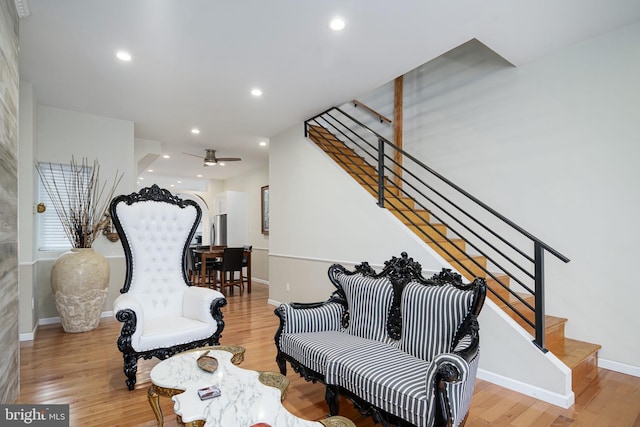 sitting room featuring stairs, wood finished floors, baseboards, ceiling fan, and recessed lighting