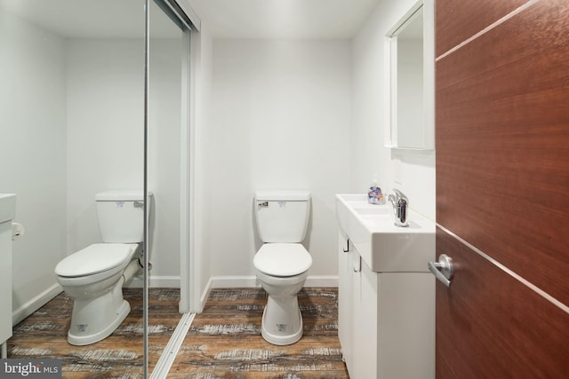 bathroom featuring vanity, baseboards, wood finished floors, and toilet