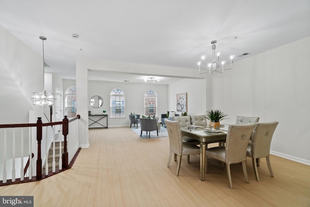 dining room featuring light wood-style flooring, baseboards, and an inviting chandelier