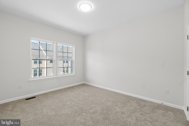carpeted empty room with visible vents and baseboards