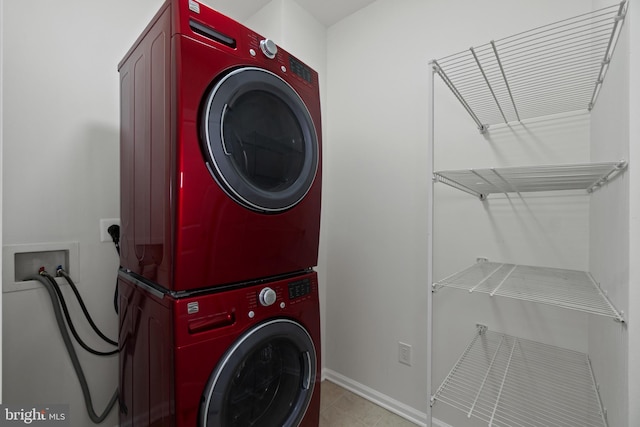 laundry area with baseboards, stacked washing maching and dryer, laundry area, and light tile patterned floors