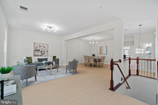 living room featuring a notable chandelier, wood finished floors, and visible vents