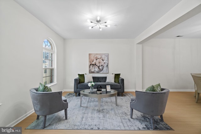 living room with baseboards, wood finished floors, and a chandelier