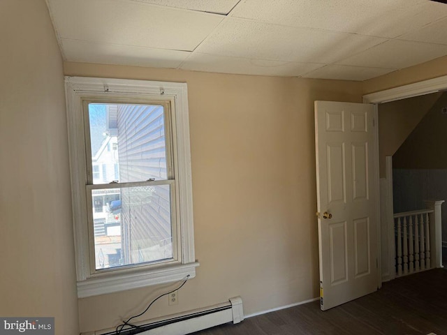 unfurnished room featuring a baseboard heating unit, baseboards, and dark wood-type flooring