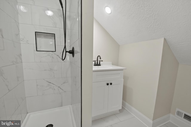 full bathroom featuring visible vents, vanity, vaulted ceiling, and tiled shower