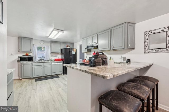 kitchen with dishwashing machine, gray cabinets, freestanding refrigerator, and stainless steel microwave