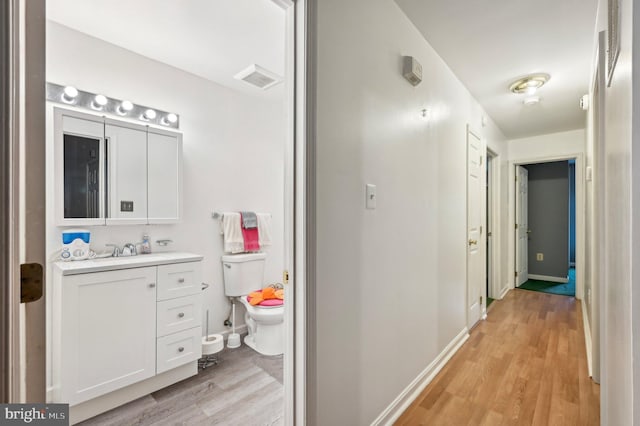 bathroom featuring wood finished floors, toilet, vanity, and baseboards