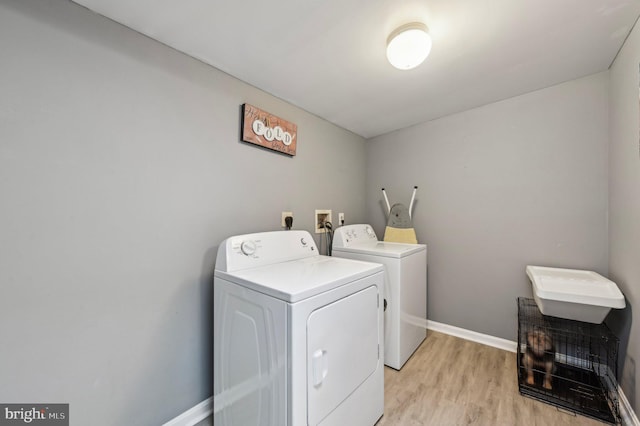 laundry room featuring washing machine and clothes dryer, light wood-style flooring, and baseboards
