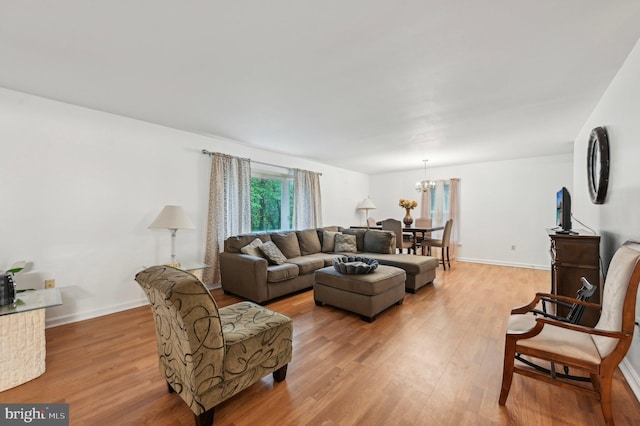 living room with light wood finished floors, a chandelier, and baseboards