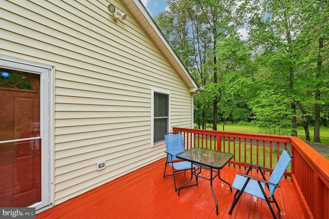 deck with outdoor dining space and view of scattered trees
