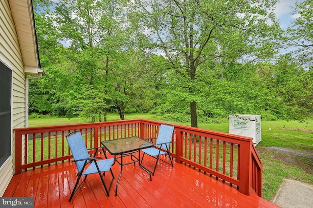 wooden terrace featuring outdoor dining space and a lawn