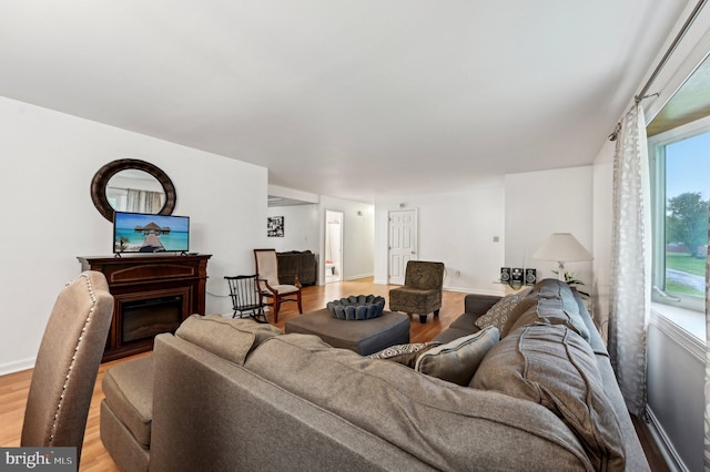 living area with light wood-style floors, a fireplace, and baseboards