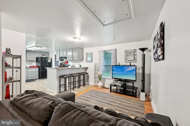 living room with attic access, light wood-style flooring, and baseboards