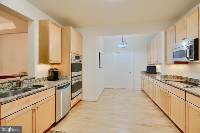 kitchen with light wood finished floors, light brown cabinets, stainless steel appliances, and a sink