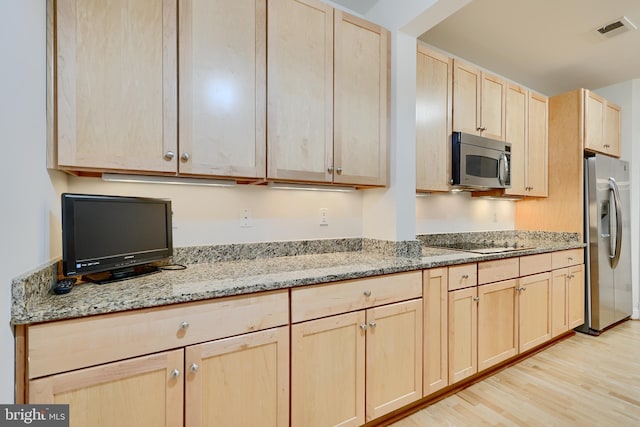 kitchen with light wood-style flooring, light brown cabinetry, visible vents, light stone countertops, and appliances with stainless steel finishes