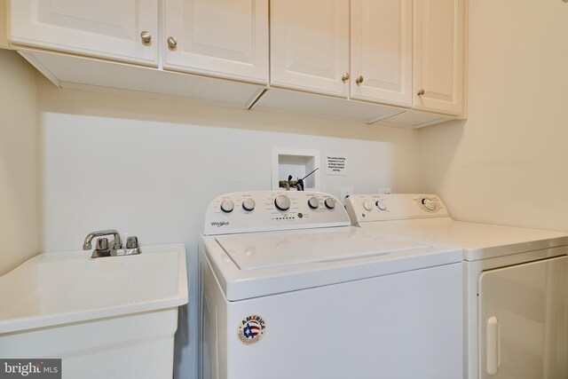 washroom featuring washing machine and clothes dryer, a sink, and cabinet space