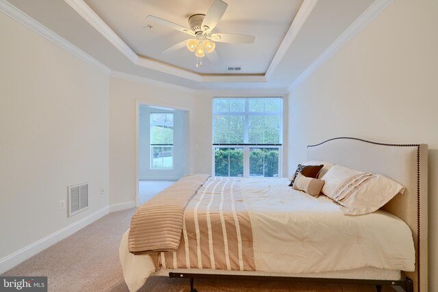 carpeted bedroom with a raised ceiling, visible vents, baseboards, and ornamental molding