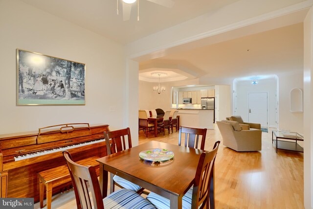 dining space featuring light wood-type flooring and ceiling fan with notable chandelier