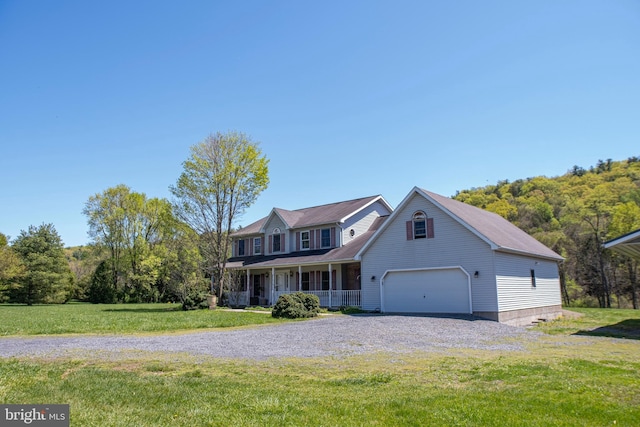 view of front of property featuring a porch, gravel driveway, a front yard, and a garage