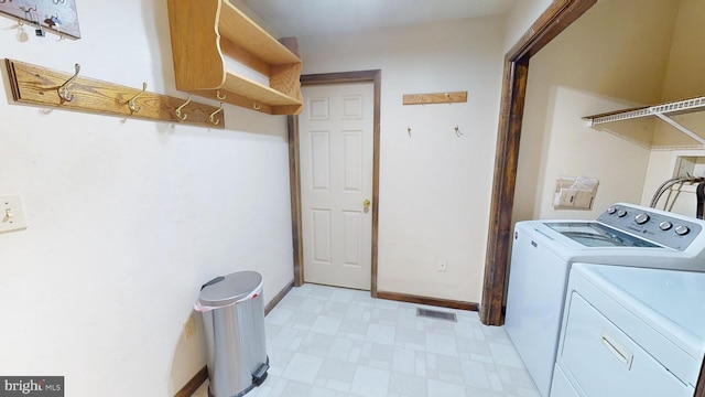 clothes washing area with laundry area, visible vents, washing machine and clothes dryer, baseboards, and light floors