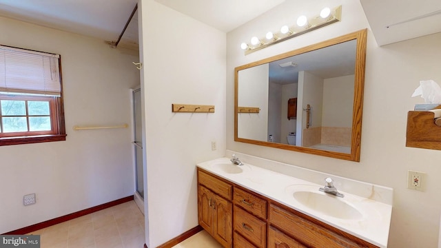 full bath with double vanity, a sink, baseboards, and a shower with shower door