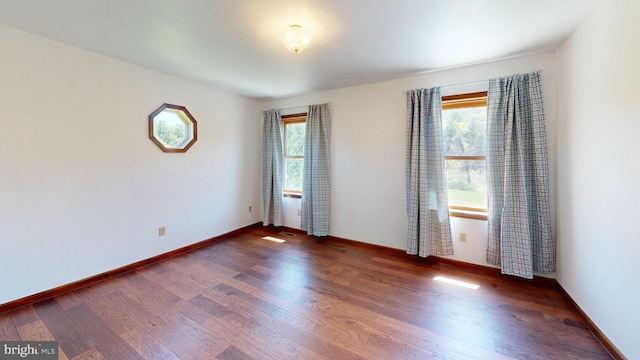 unfurnished room with baseboards and wood finished floors