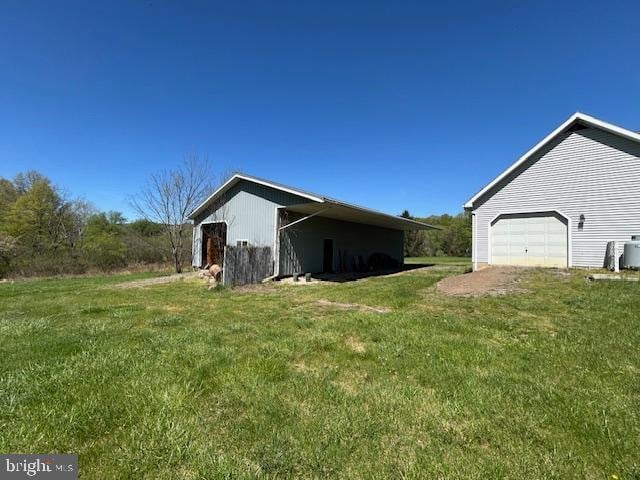 view of side of home with a lawn, a garage, an outbuilding, and a pole building