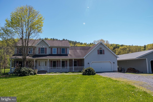 colonial-style house with covered porch, an attached garage, driveway, and a front yard
