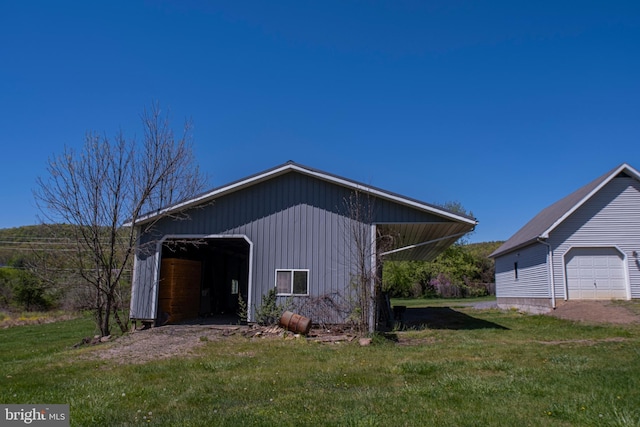 exterior space with a detached garage, a lawn, and an outdoor structure