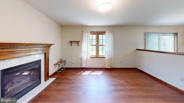 unfurnished living room featuring baseboards, a fireplace, and wood finished floors