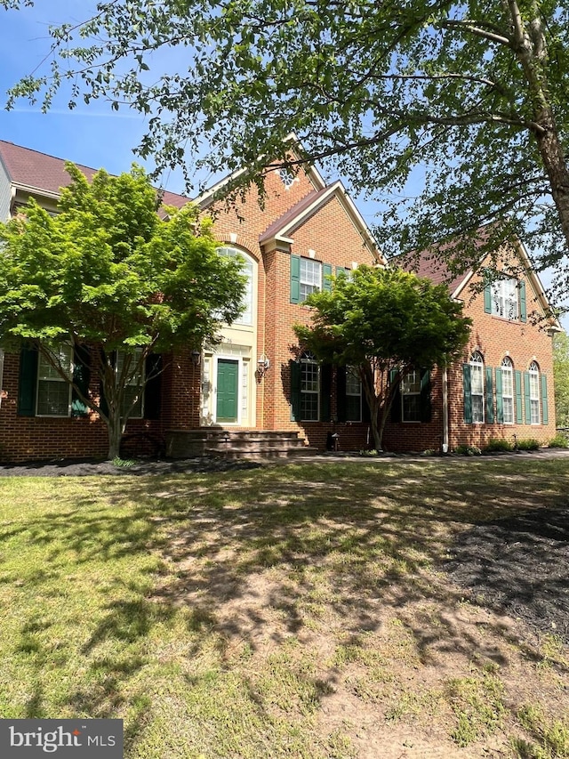 view of front of home featuring brick siding and a front lawn