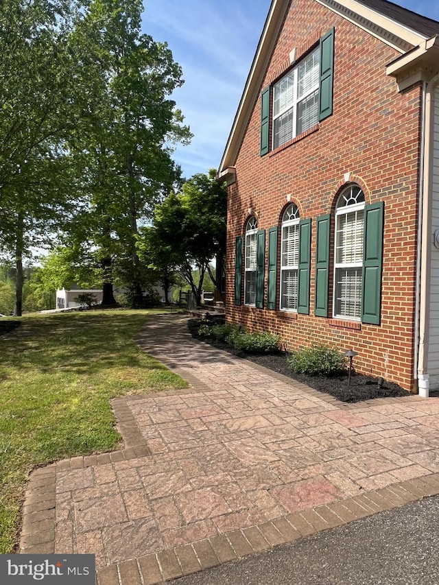 view of property exterior with brick siding and a lawn