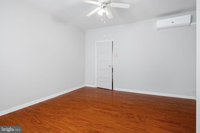 empty room featuring ceiling fan, wood finished floors, baseboards, and a wall unit AC