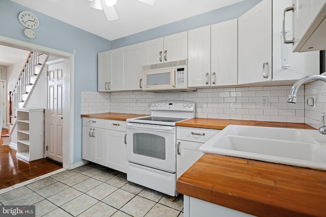 kitchen featuring white cabinets, a sink, backsplash, white appliances, and butcher block counters