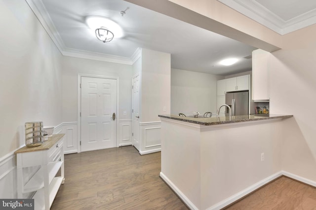 20620 Hope Spring Ter Unit 206, Ashburn, VA 20147 - kitchen with freestanding refrigerator, ornamental molding, white cabinets, wood finished floors, and a peninsula