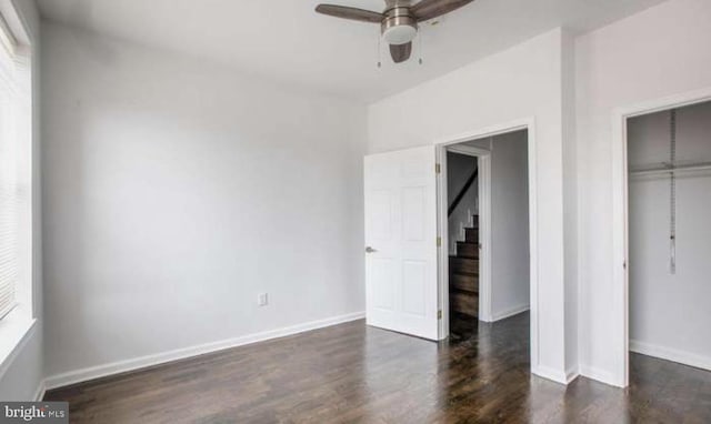 unfurnished bedroom featuring a ceiling fan, baseboards, wood finished floors, and a closet
