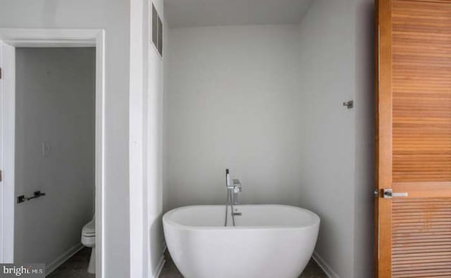 full bathroom featuring baseboards, a soaking tub, toilet, and visible vents
