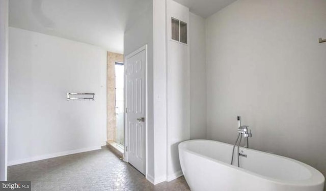 bathroom featuring visible vents, a freestanding tub, and baseboards