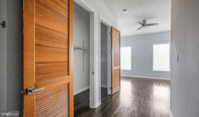 hallway with dark wood-style flooring and baseboards