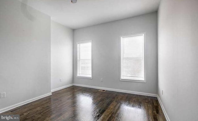 spare room with baseboards and wood finished floors