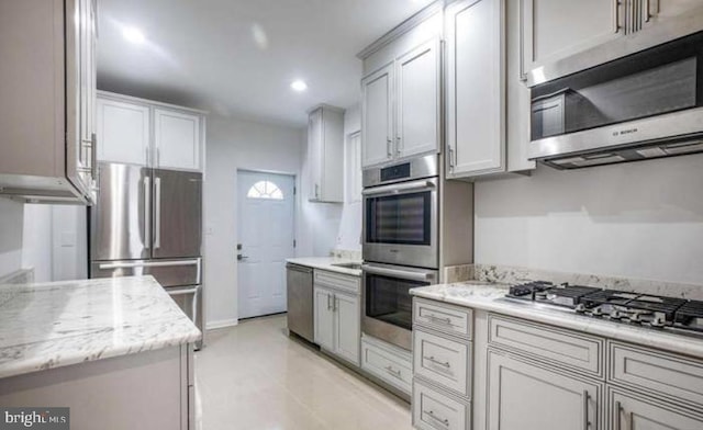 kitchen with recessed lighting, light stone counters, light tile patterned flooring, and stainless steel appliances