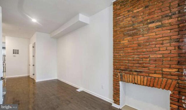 interior space with baseboards, dark wood-type flooring, and visible vents