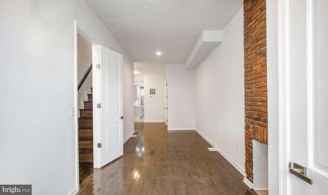 corridor featuring stairs, wood finished floors, brick wall, baseboards, and recessed lighting