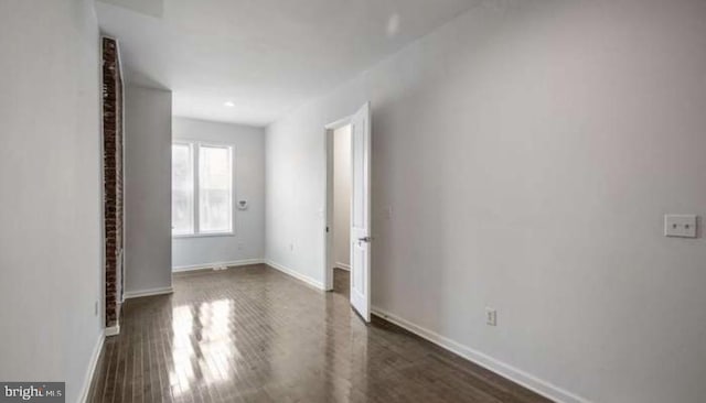 empty room featuring baseboards and dark wood-style flooring