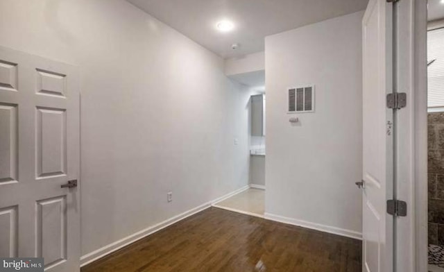 hallway with visible vents, baseboards, and dark wood-type flooring