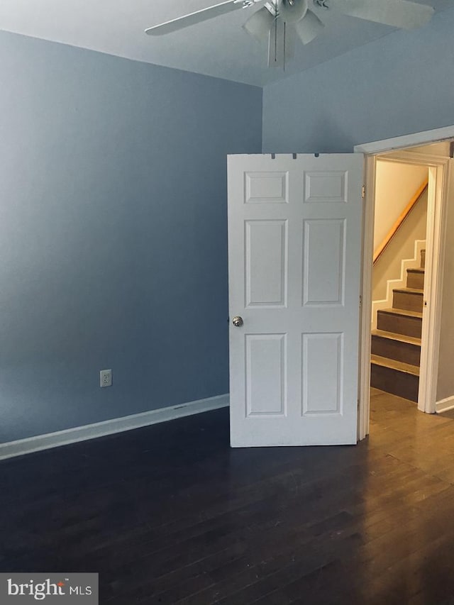 unfurnished bedroom with baseboards, a ceiling fan, and dark wood-style floors