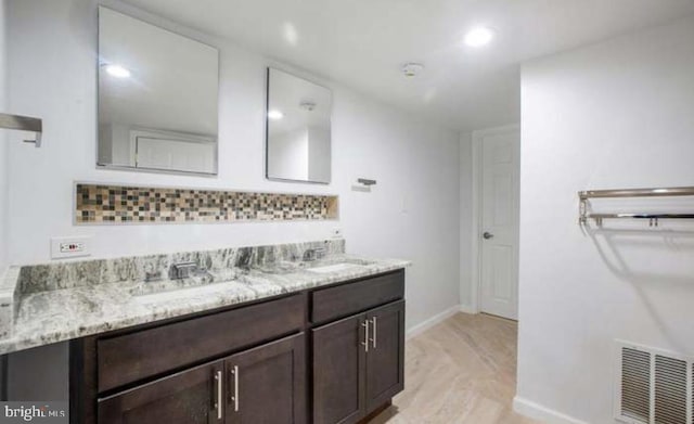 bathroom featuring double vanity, baseboards, visible vents, and a sink