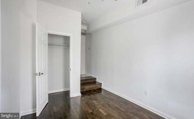 unfurnished bedroom with baseboards, visible vents, wood finished floors, and a closet