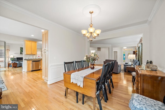 dining space featuring crown molding, light wood-style flooring, and a notable chandelier