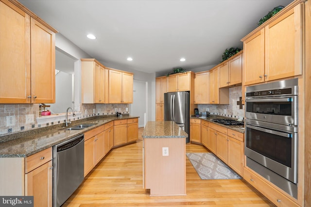 kitchen with a sink, light wood finished floors, appliances with stainless steel finishes, and light brown cabinetry